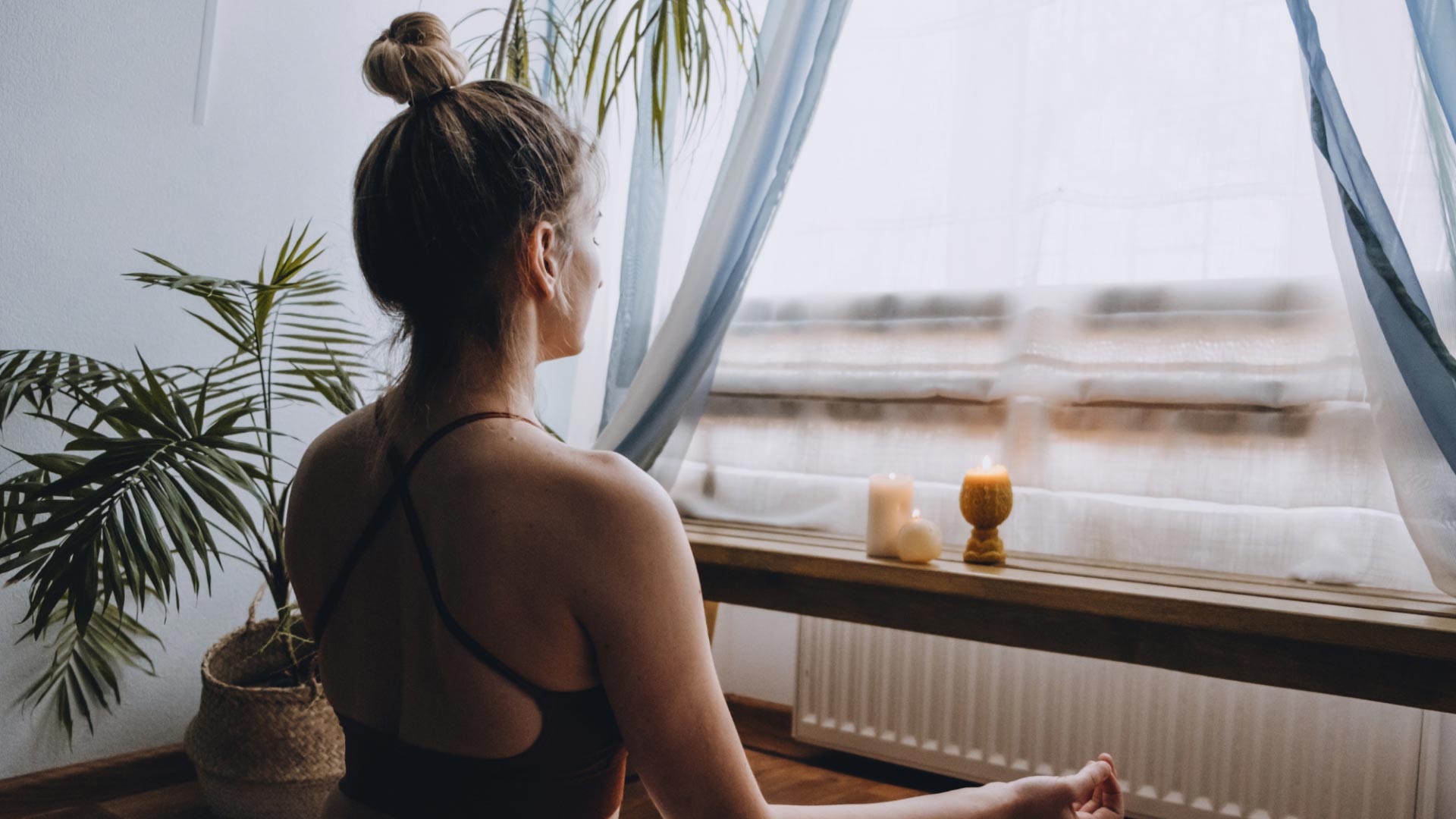 Heilung durch Meditation: Frau meditiert am Fenster